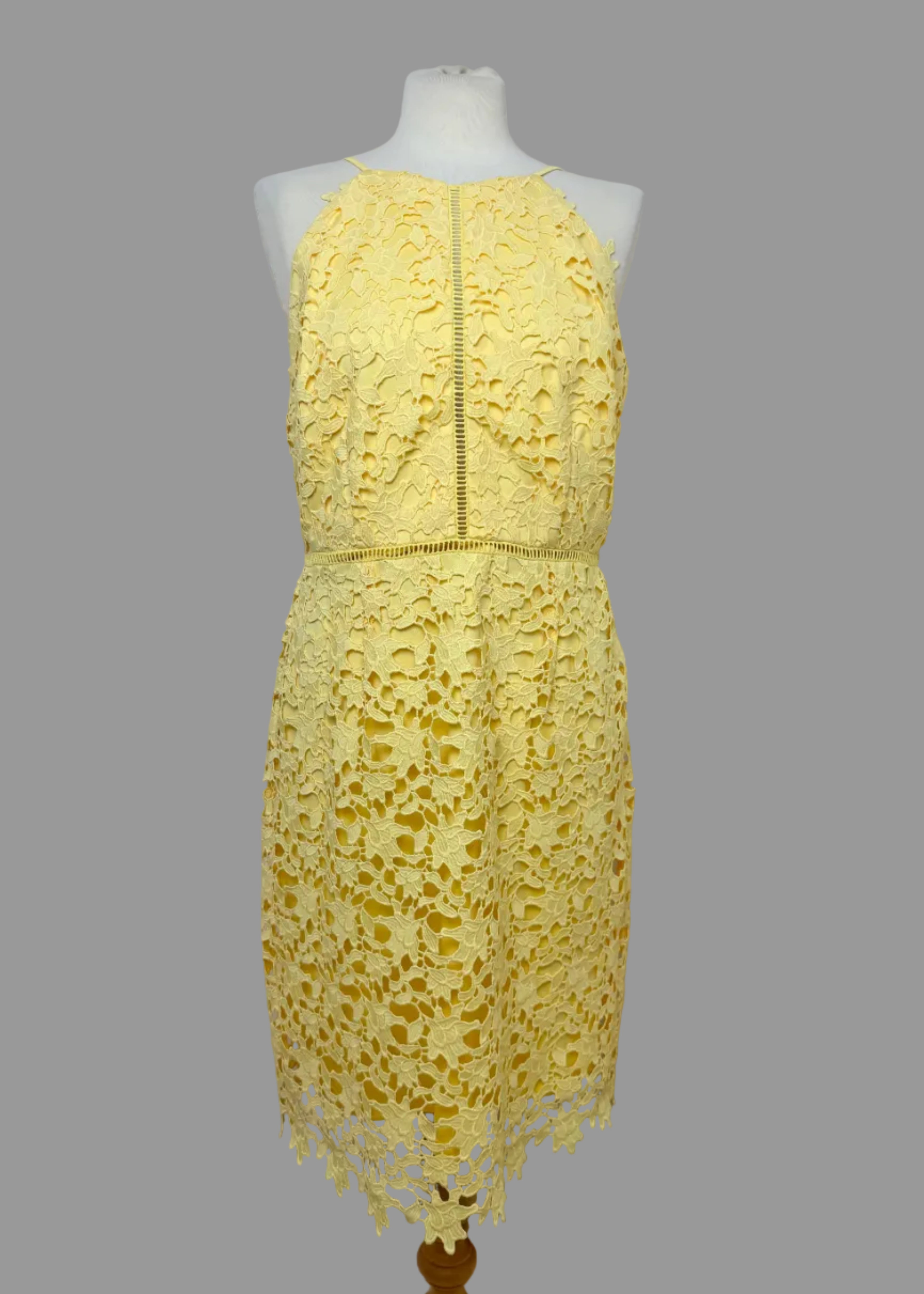Yellow lace dress on a mannequin against a white wall