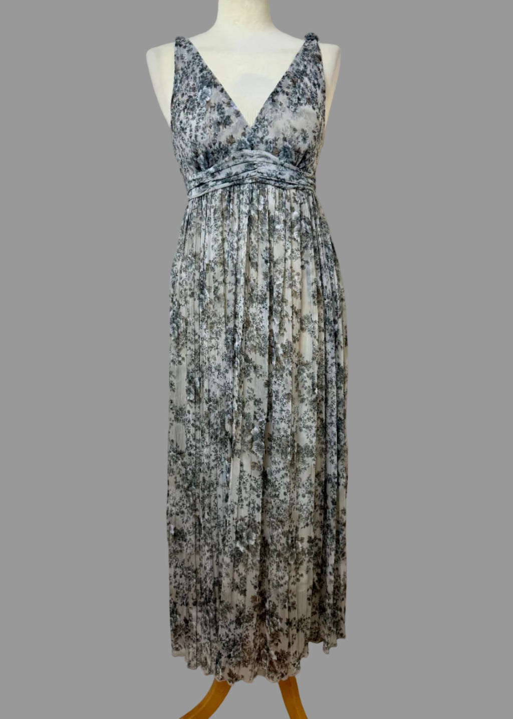 Floral patterned dress on a mannequin against a plain wall.