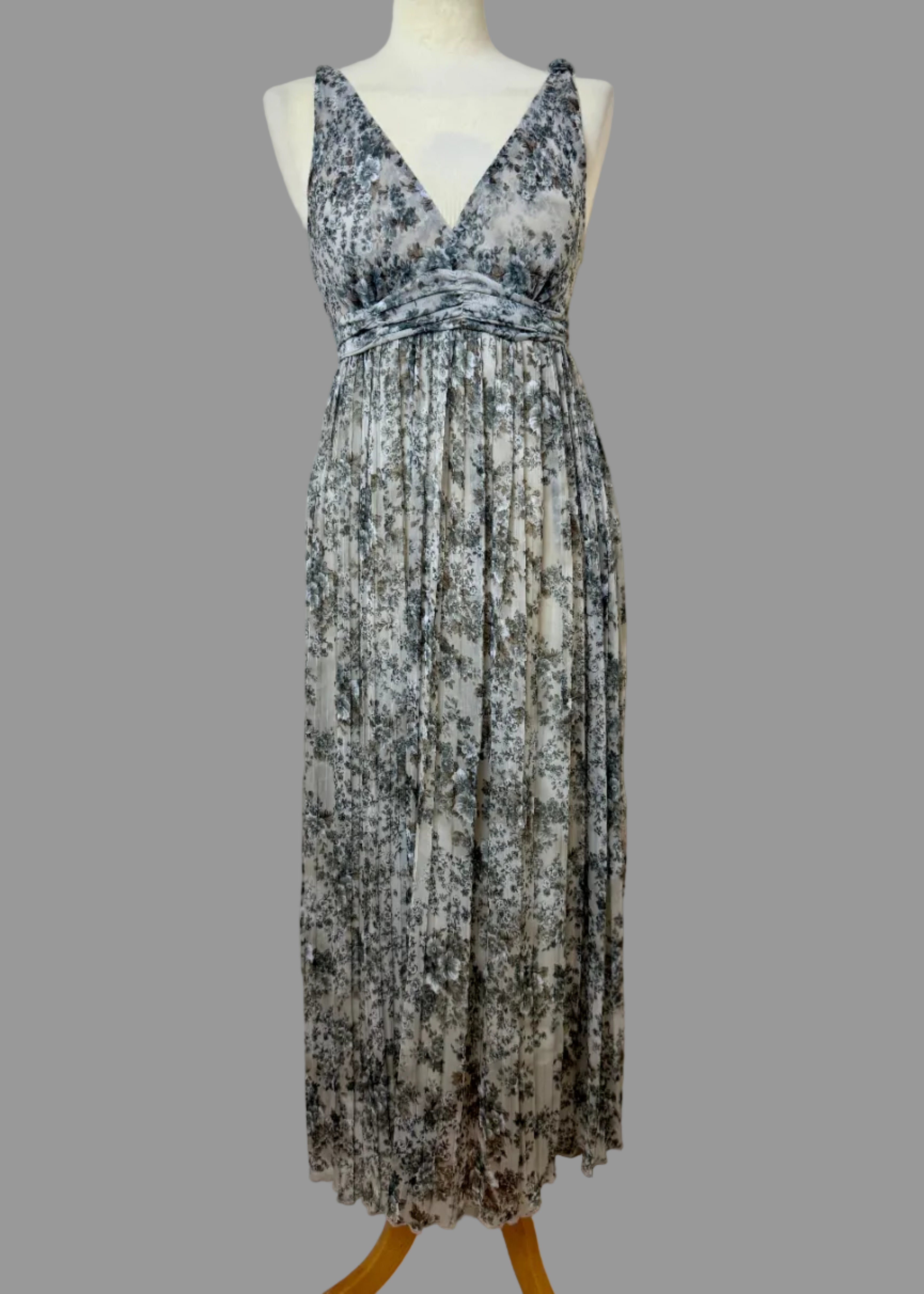 Floral patterned dress on a mannequin against a plain wall.